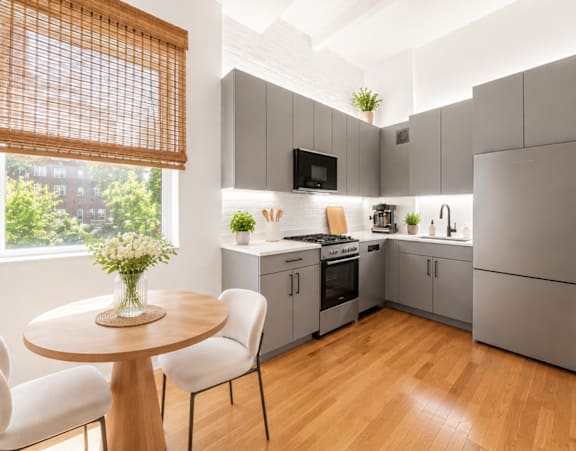 A modern kitchen with a table and chairs by the window.