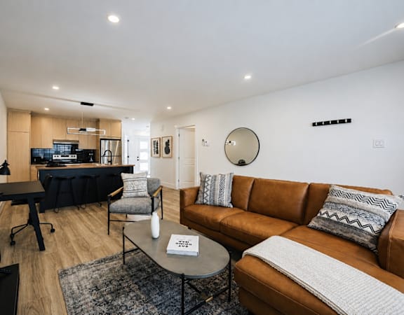 A modern living room with a brown couch and a black piano.