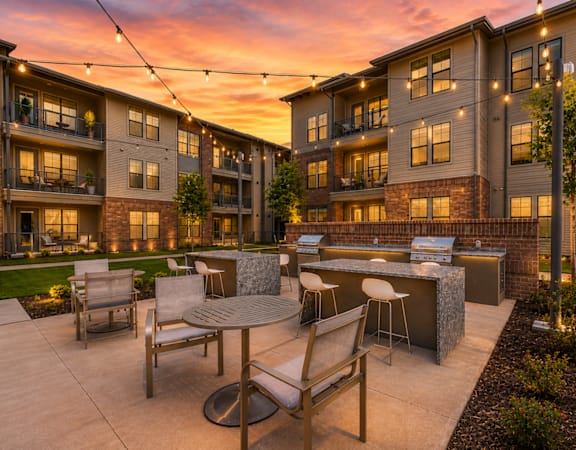 Outdoor grilling station and resident courtyard illuminated at sunset at One Preston Station Apartments.