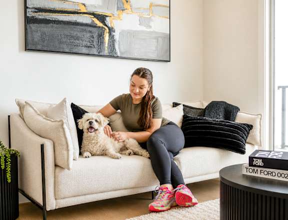 A woman is sitting on a couch with her dog.