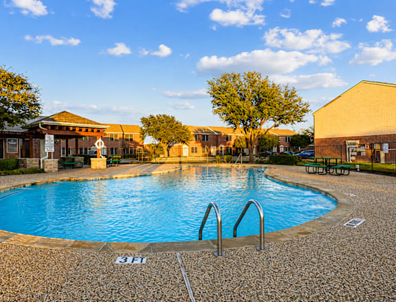 A swimming pool surrounded by a stone patio and trees.