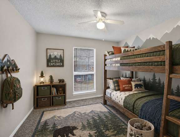 A room with a bunk bed, a rug with a bear on it, and a wall hanging that says "Little Explorer".