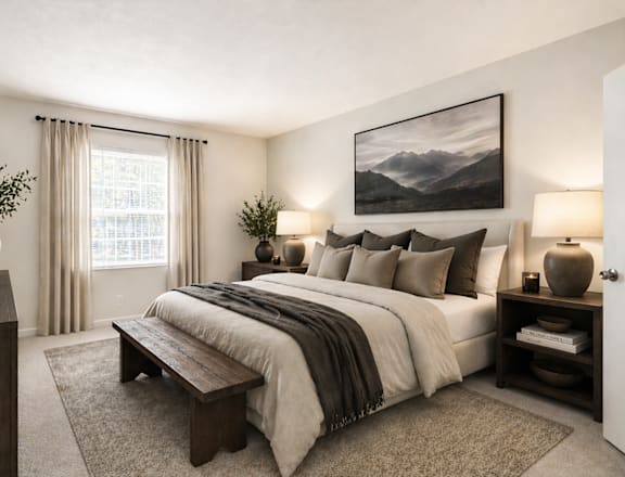 A bedroom with a large bed, a bench, and a painting on the wall.