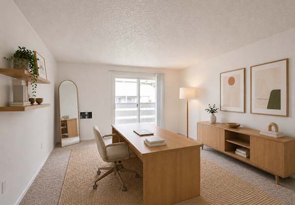 A room with a desk, chair, and shelves with plants.