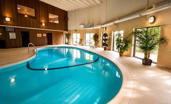 A large indoor swimming pool with a blue tinted water.