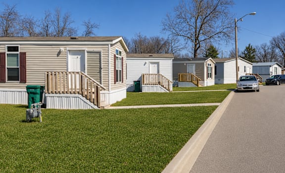 A row of mobile homes with a car parked in front of the last one.