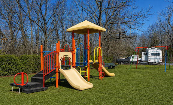 A playground with a yellow slide and a red and blue play structure.