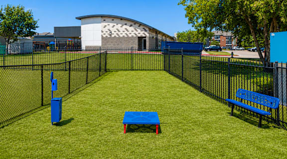 A park with a blue bench and a blue trash can.