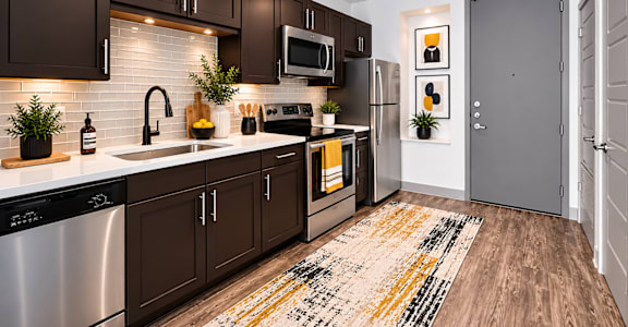 A modern kitchen with dark brown cabinets and a white backsplash.