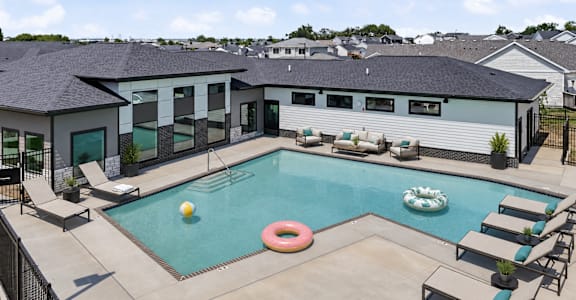 A pool with a yellow ball and a pink inner tube.