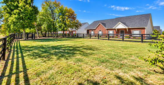 A house with a fence and trees in front of it.