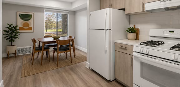 A kitchen with a white refrigerator, a dining table with chairs, and a stove top oven.