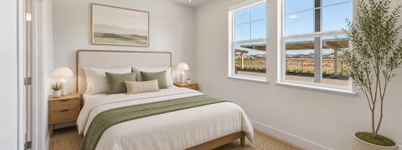 A bedroom with a bed, a ceiling fan, and a window with a view of a building outside.