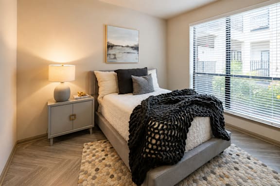 A bedroom with a bed, nightstand, and window.