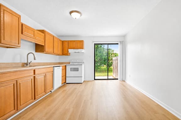 A kitchen with wooden cabinets and a white wall.