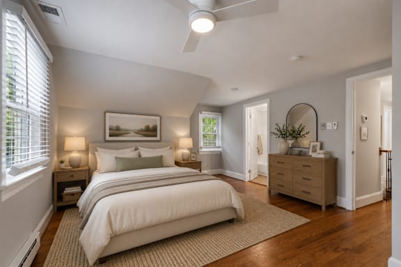 A bedroom with a large bed, a dresser, and a painting on the wall.