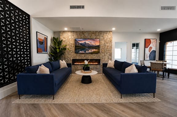A living room with two blue couches and a fireplace.