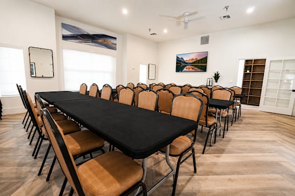 A long black table surrounded by chairs in a room.