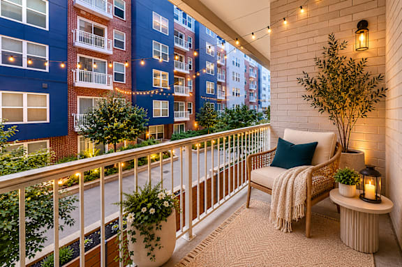 A balcony with a chair, pillow, and a lantern.