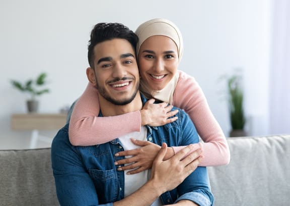 a man and woman sitting on a couch with their arms around each other