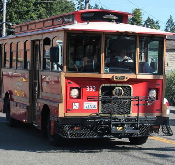 a red trolley car is driving down the street