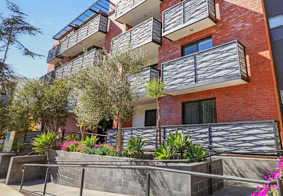 an apartment building with a staircase and flowers in front of it