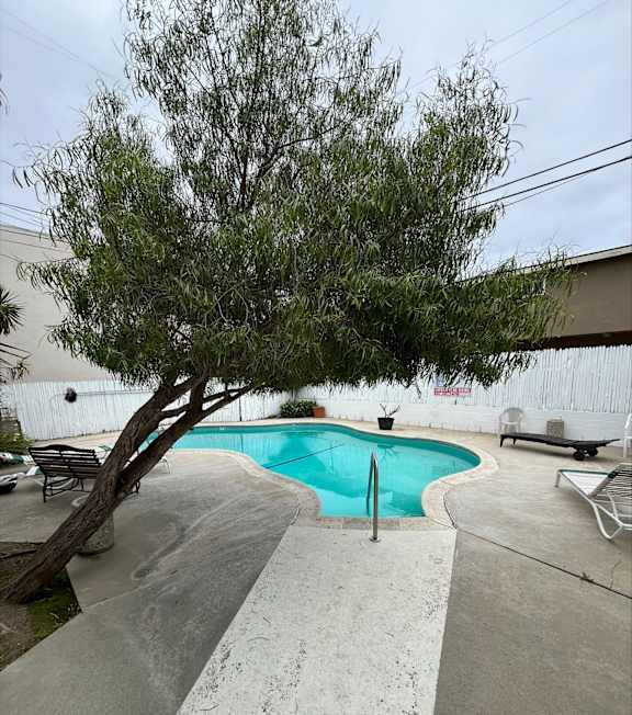 A pool with a hot tub and lounge chairs in front of a building.