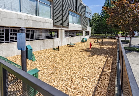 A playground with a green fence and a red fire hydrant.