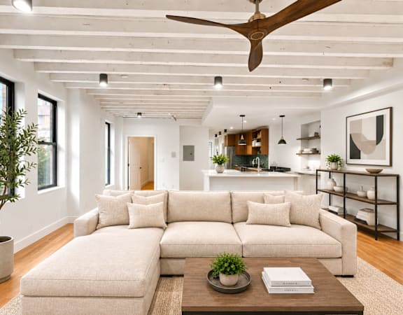 A living room with a large couch and a tree in a pot.