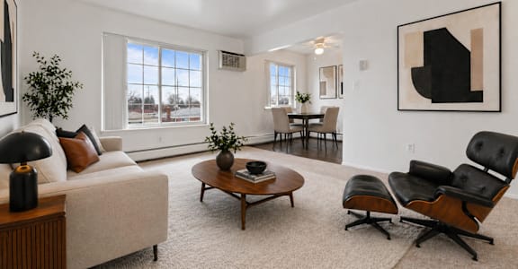 A living room with a white couch, a coffee table, and a large painting on the wall.