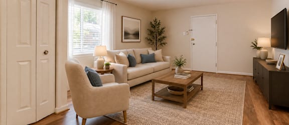 A living room with a beige sofa, a chair, a coffee table, and a ceiling fan.