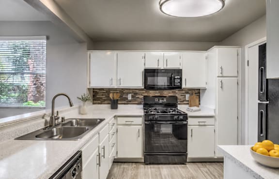 A modern kitchen with white cabinets and a black stove top oven.