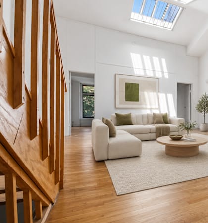 A living room with a staircase on the left and a couch and coffee table in the center.