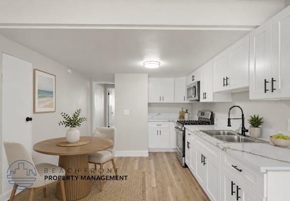 A kitchen with white cabinets and a round table with chairs.