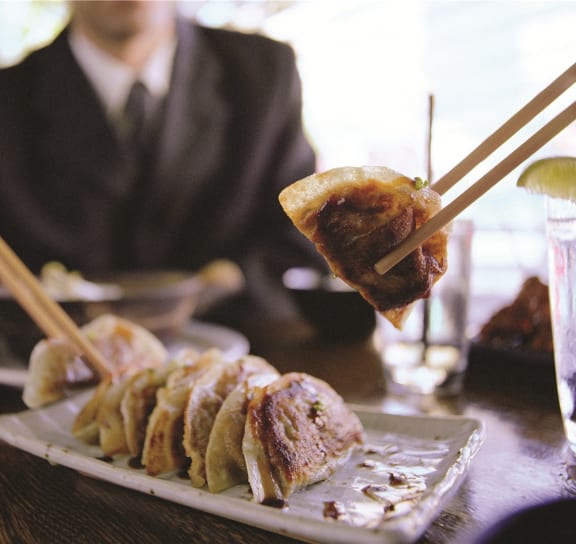 a man sitting at a table eating food with chopsticks