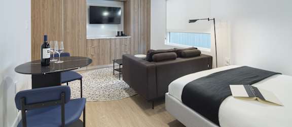 a hotel room with a bed and a table with a bottle of wine