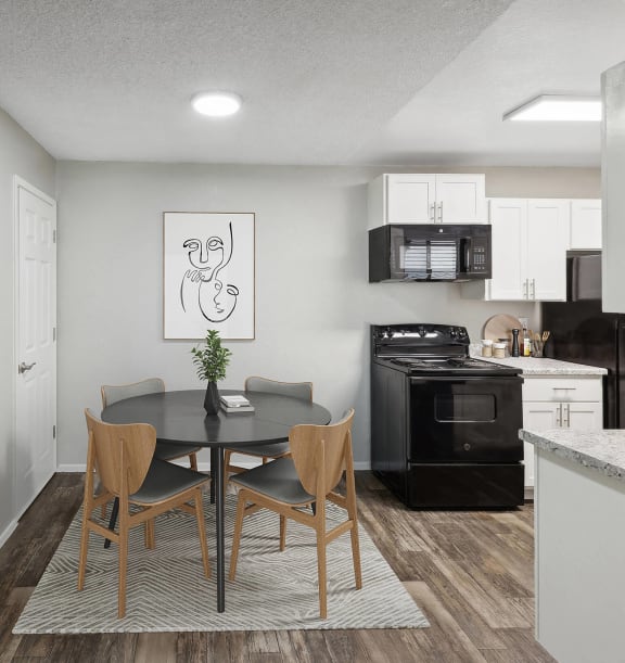 Model Dining Room with Wood-Style Flooring and View of Kitchen with White Cabinets at Solano Springs Apartments located in Tucson, AZ-WELCOME.