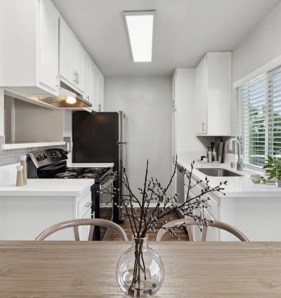 Model Kitchen with White Cabinets and Wood-Style Flooring at Colonnade at Fletcher Hills Apartments in El Cajon, CA-WELCOME.