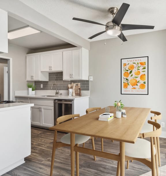 Model apartment dining room with a table and chairs and the kitchen and a ceiling fan