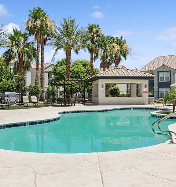 Dog-Friendly Apartments in East Las Vegas, NV - Monterra - A Swimming Pool With Palm Trees, Lounge Chairs, Shaded Seating, And Community Buildings.