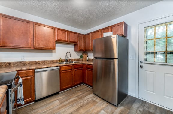A kitchen with wooden cabinets and a stainless steel refrigerator.