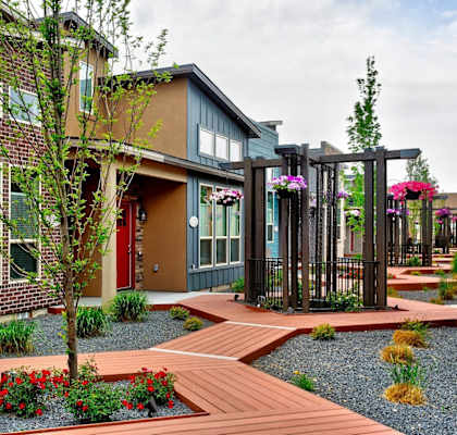 A modern house with a red door and a wooden walkway leading to the entrance.