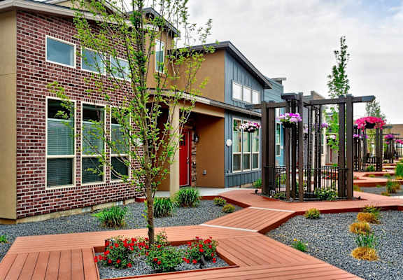 A modern house with a red door and a wooden walkway leading to the entrance.