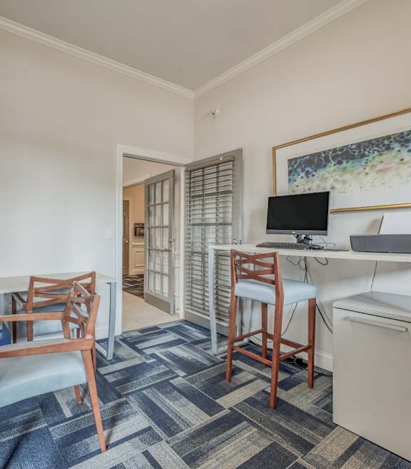 A room with a desk, chair, and a framed picture on the wall.