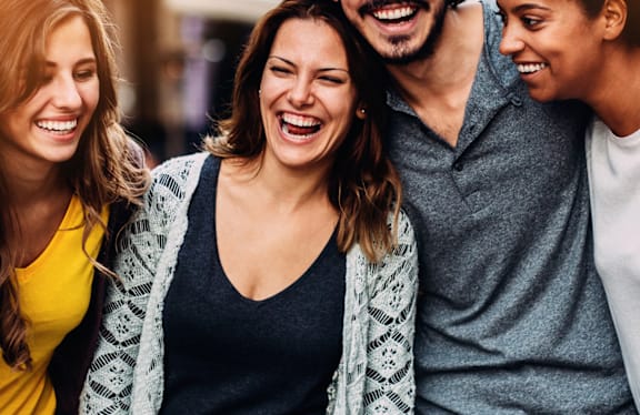 Four people standing close together and laughing.