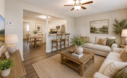 A living room with a white couch, a wooden coffee table, and a ceiling fan.