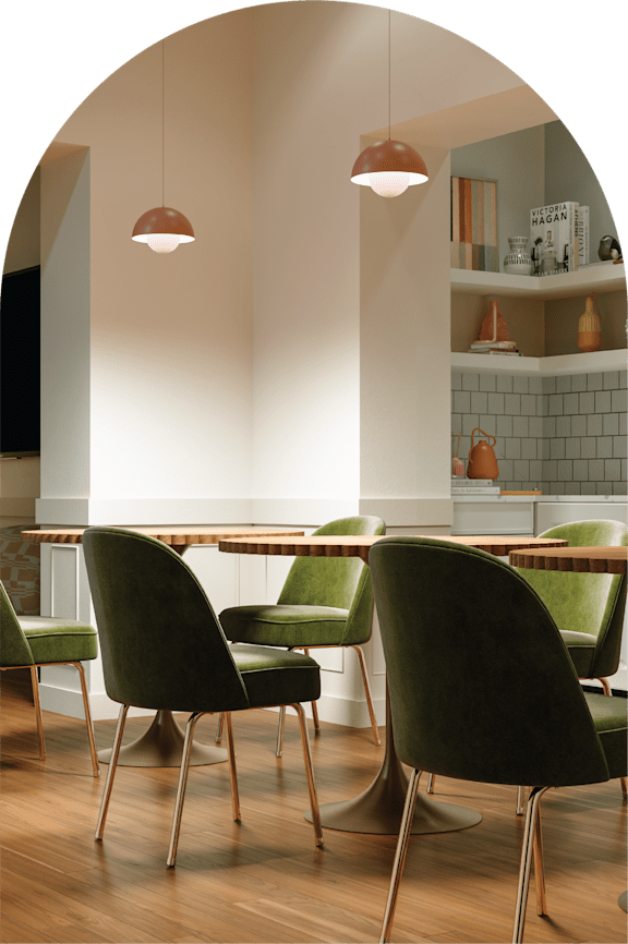 A modern dining room with green chairs and pendant lights.
