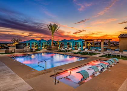 A pool area with a sunset in the background.
