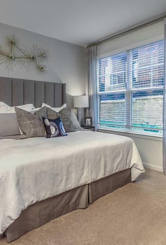 A bedroom with a large bed and a nightstand with a plant on it.