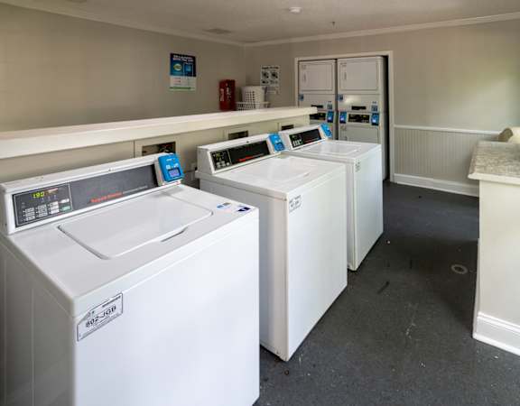 four washing machines in a row in a laundry room
